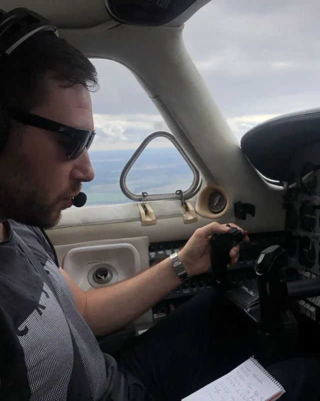 Dimitri Baitinger im Cockpit eines Kleinflugzeugs, mit Headset und Notizblock